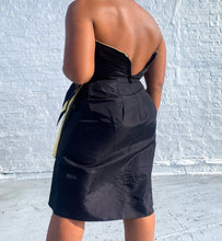 Load image into Gallery viewer, Sleek 80's cocktail dress with gold and black bow detail. Shown unzipped in the back.